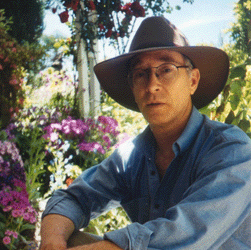 Photo of Daan Spijer wearing an Akubra hat and relaxing in a colourful garden.