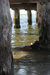 Rosebud Pier on Port Philip: looking along under the pier between two pilons with aother two pilons in the distance; sun playing on the water creating light and shade.